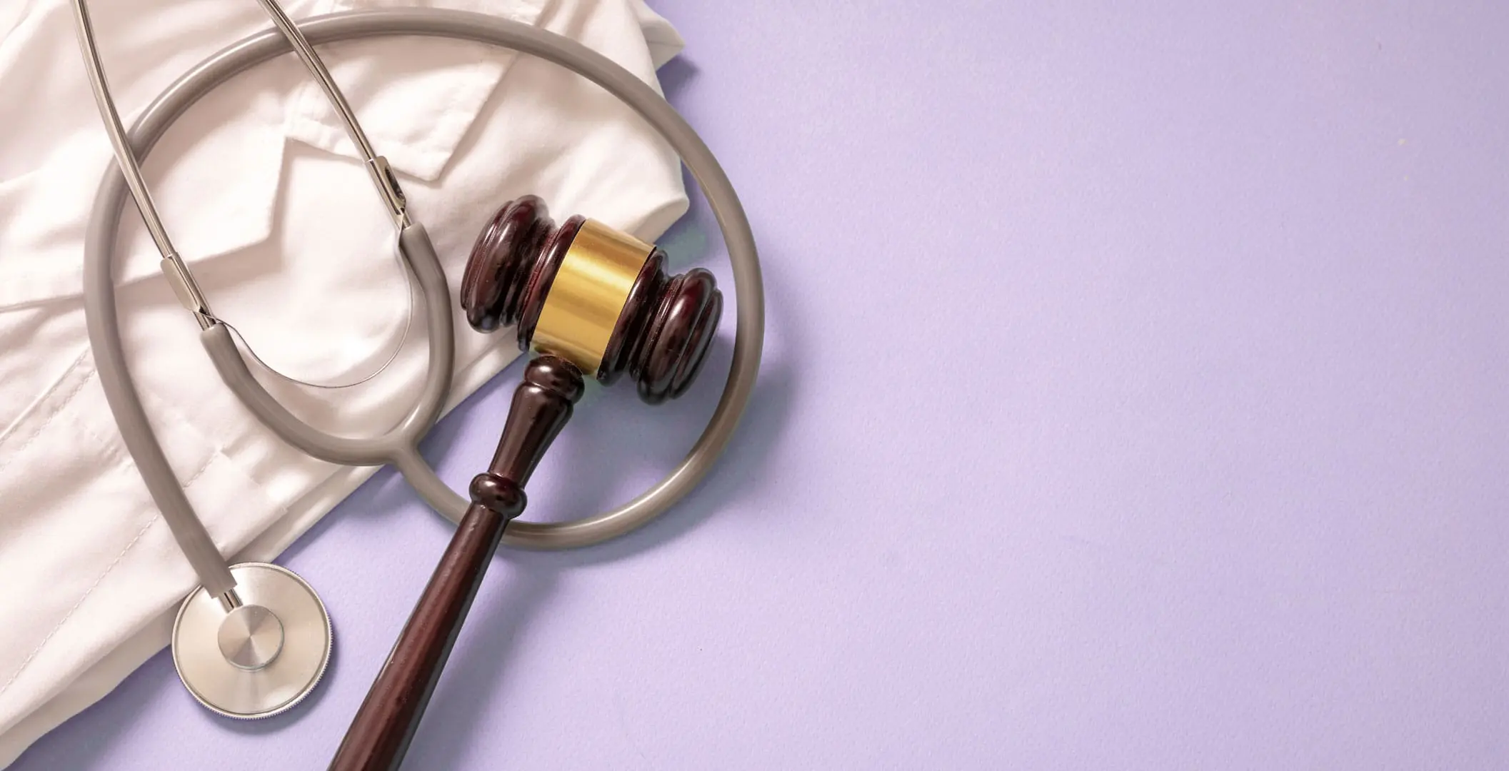 a gavel and a stethoscope on a purple background symbolizing the intersection of the legal and medical system in AOT programs.